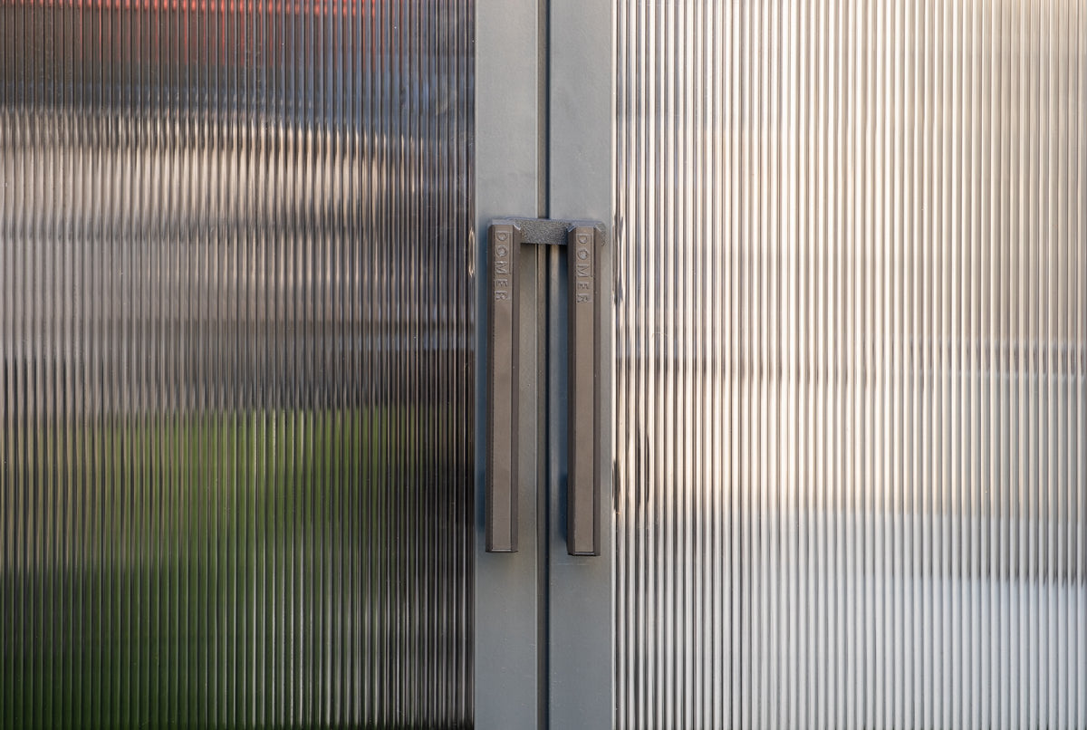 Close-up of DOMER-branded door handles and ribbed panels on the Standard Slate shed with Black profile. #Profile colour_Black